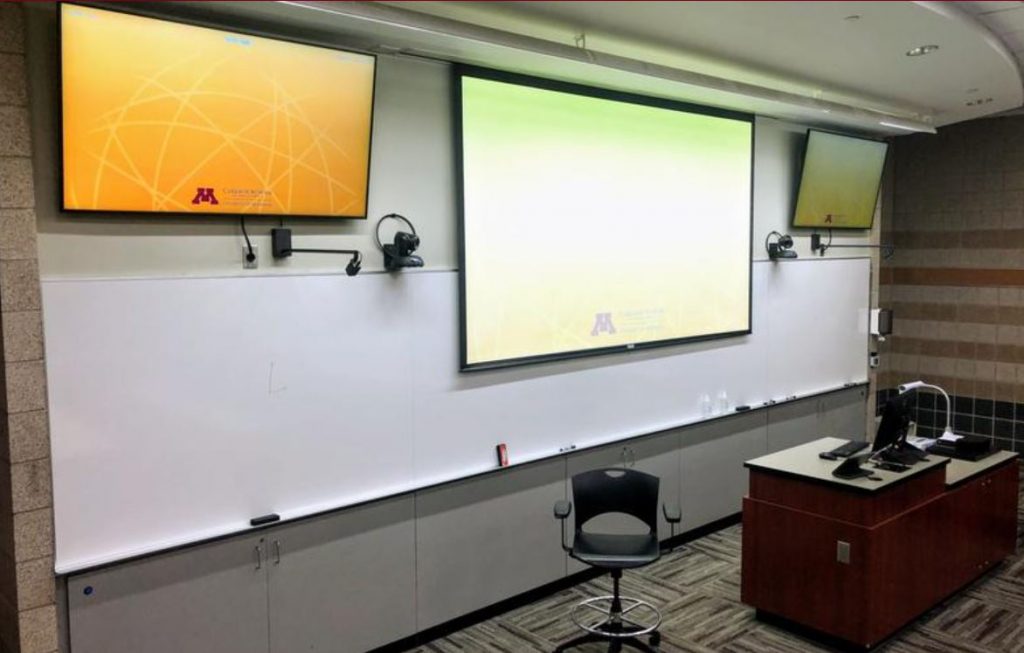 A Hyflex-friendly classroom at the University of Minnesota has large display monitors and cameras at the front of the room.